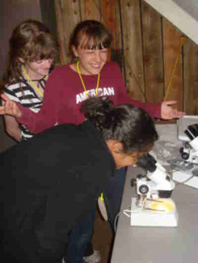 Schafer looking at fish scales with Destiny and Laura looking on.